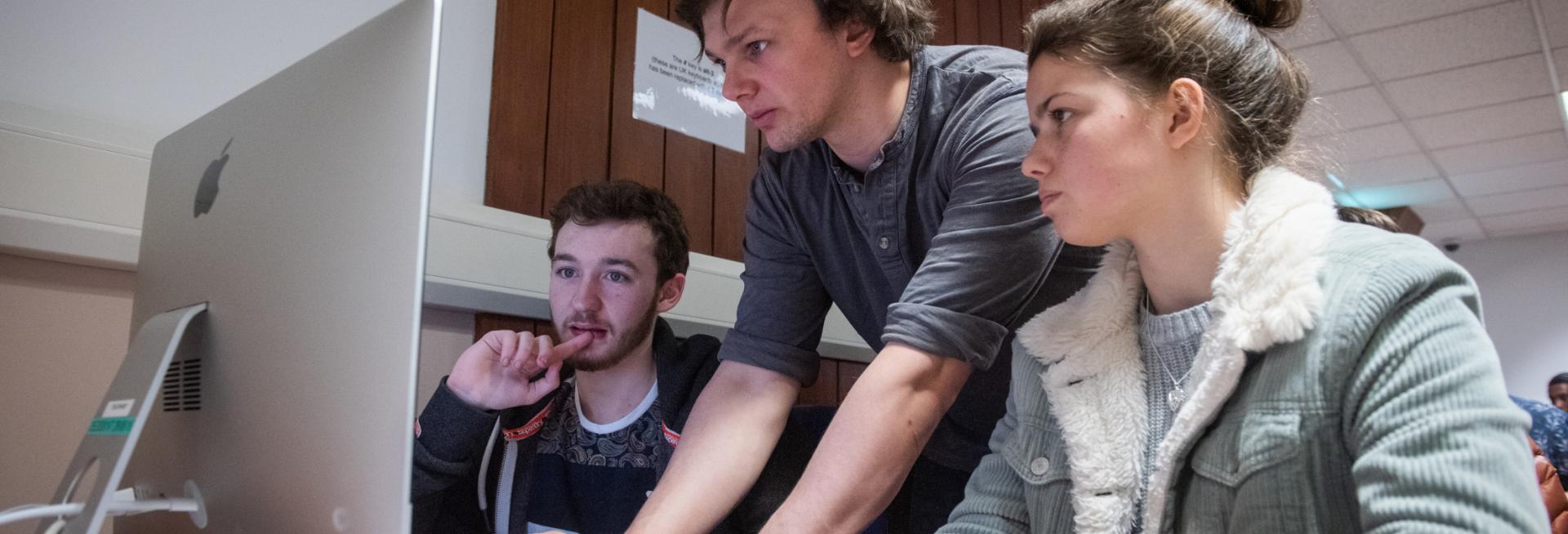 Students working on computer with demonstrator 