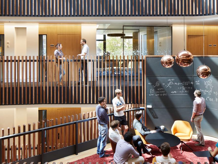 Theoretical physicists working at a blackboard collaboration pod in the Beecroft building.